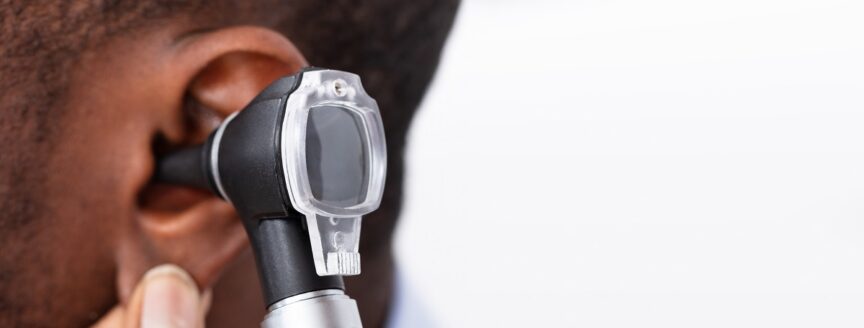 African Doctor Examining Male Patient's Ear With Otoscope